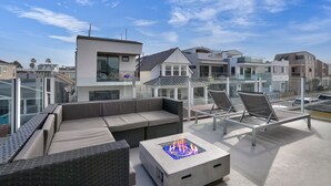 Um terraço no telhado com área de estar ao ar livre, lareira e vista para as casas vizinhas.