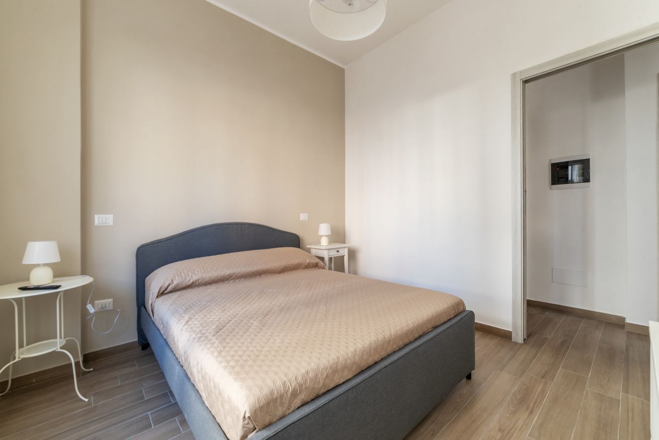 A bedroom with a bed, bedside tables, and a wardrobe.