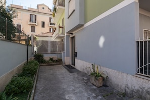 A narrow alleyway with a small courtyard, a door, and a window with a metal grill.