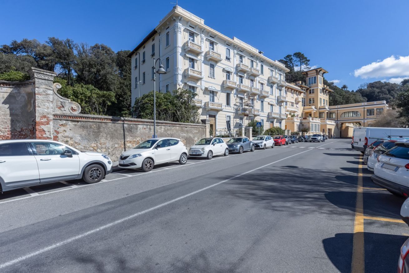 Ein mehrstöckiges Gebäude mit Balkonen, parkenden Autos und blauem Himmel.