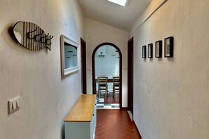 A hallway with a wooden bench, a fish-shaped wall decoration, a framed mirror, and a series of framed pictures on the wall. - GuestHost - Comfortable apartment of approximately 64 m2, able to accommodate up to 4 people, located on the fourth floor of a building without a lift. The accommodation is located in an area full of all services and boasts a wonderful view of the San Te (Lerici)