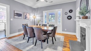 Une salle à manger avec une table et des chaises en bois, un ventilateur de plafond et une cheminée.