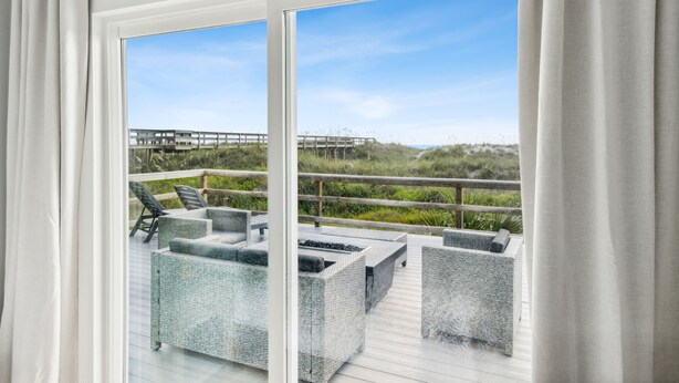 Un balcón con mobiliario de mimbre, vistas a la playa y una terraza de madera.