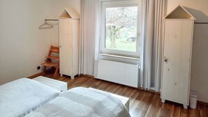 A room with two beds, a radiator, a window with curtains, and a chair. - Zum Koppelblick by Interhome (Woldegk)
