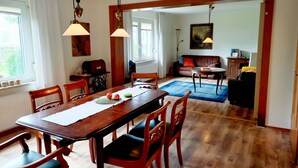 A dining area with a wooden table and chairs, a blue rug, and a kitchen in the background. - Zum Koppelblick by Interhome (Woldegk)