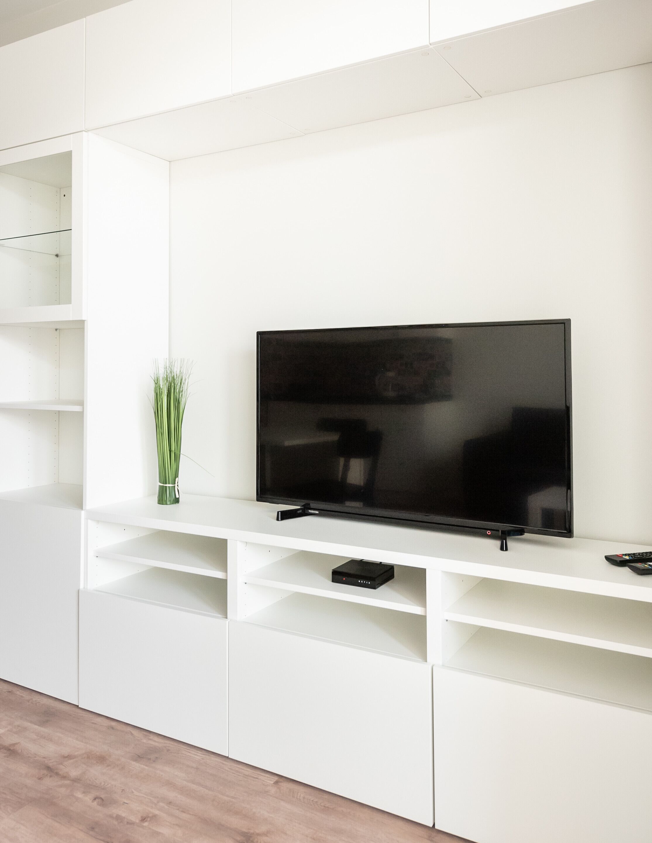 Een moderne woonkamer met een flatscreen televisie bevestigd aan een witte meubelunit.
