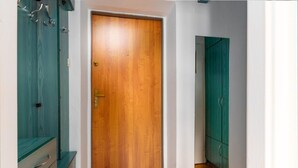 A hallway with a wooden door, teal cabinets, and a white wall. - Rynek Wrocław Cosy Studio (Wrocław)