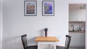 A small dining area with two black chairs, a wooden table, and two framed pictures on the wall. - Rynek Wrocław Cosy Studio (Wrocław)