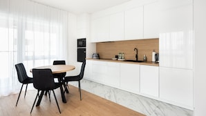 A modern kitchen with white cabinets, a wooden countertop, and a black stove. - Brzeziny Deluxe Apartment (Warszawa)