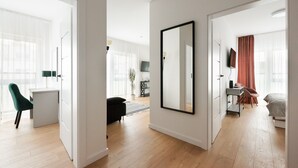 A modern, well-lit room with a large mirror, a bed, and a desk area. - Brzeziny Deluxe Apartment (Warszawa)