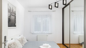 Una camera da letto con un letto, una finestra con tende leggere, un termosifone e uno specchio a parete.