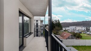 Een balkon met uitzicht op een parkeerplaats en gebouwen.