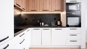 Een moderne keuken met witte kastjes, een zwart aanrecht en een inbouwoven.