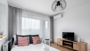 Een moderne hotelkamer met een groot bed, een televisie, een houten kast en een klein, rond tafeltje.