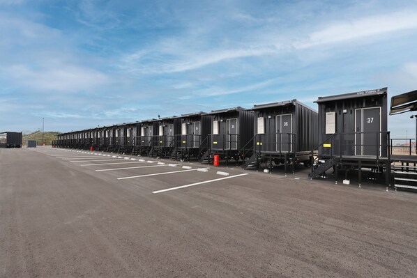 A row of uniform, industrial-style train carriages with numbered doors, parked on a flat surface with clear skies.