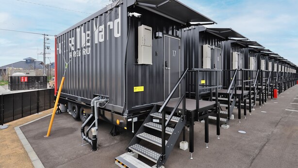 A row of black modular cabins with metal staircases and numbered doors, likely for temporary accommodation. - HOTEL R9 The Yard Kurobe (Kurobe)