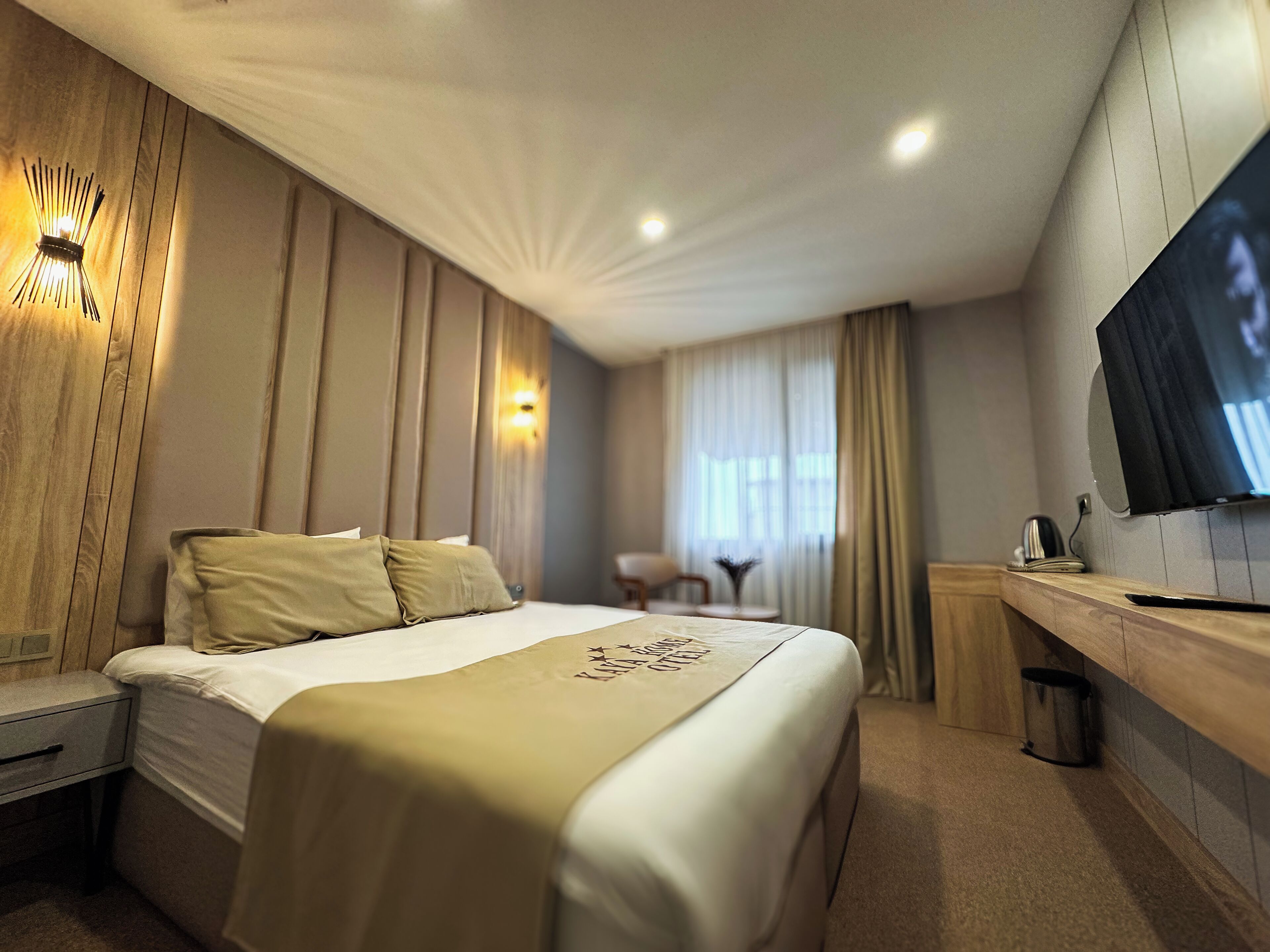 Een hotelkamer met een bed, nachtkastje, televisie en bureau met stoel.