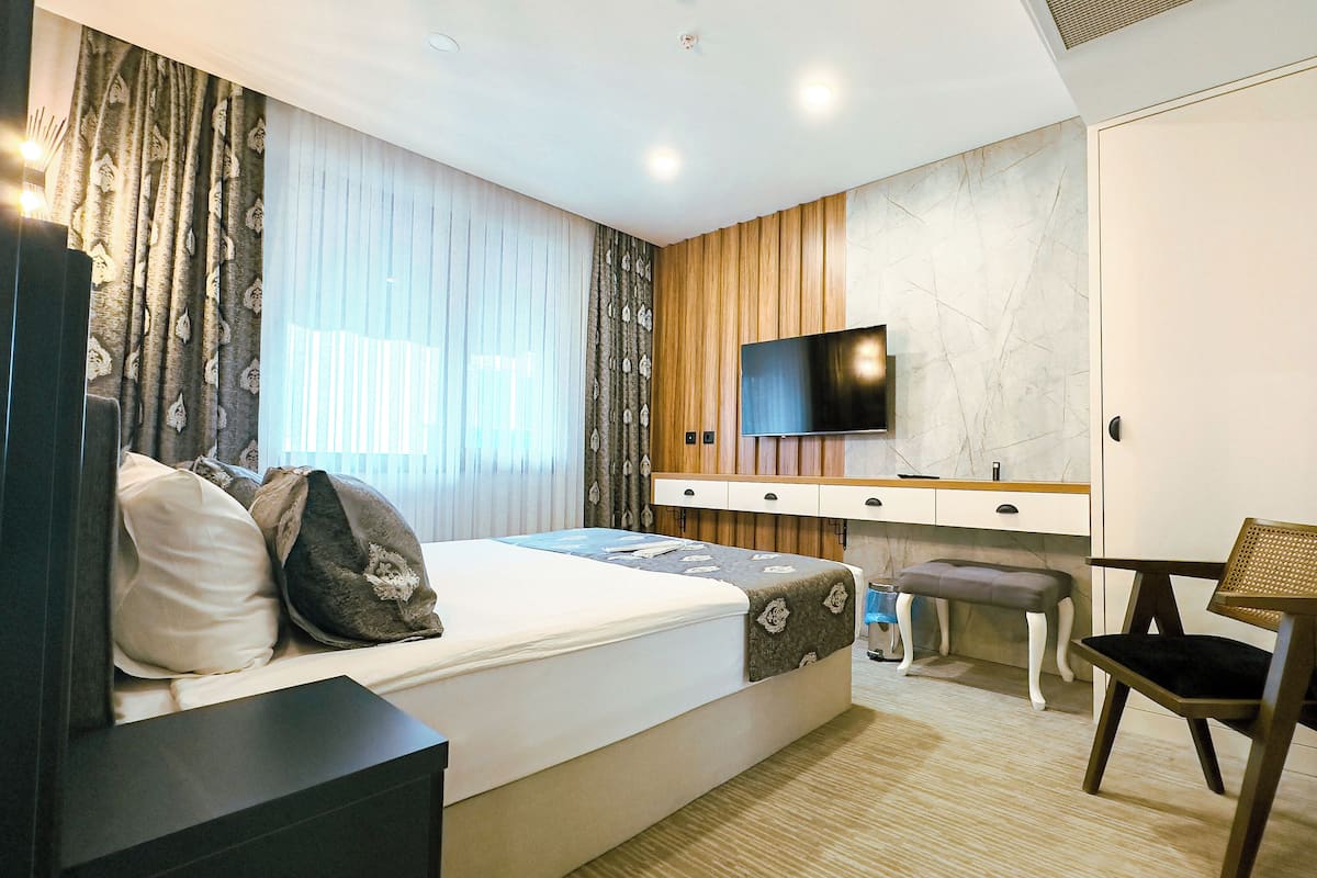 A modern bedroom with a bed, a desk, a TV, and a chair.