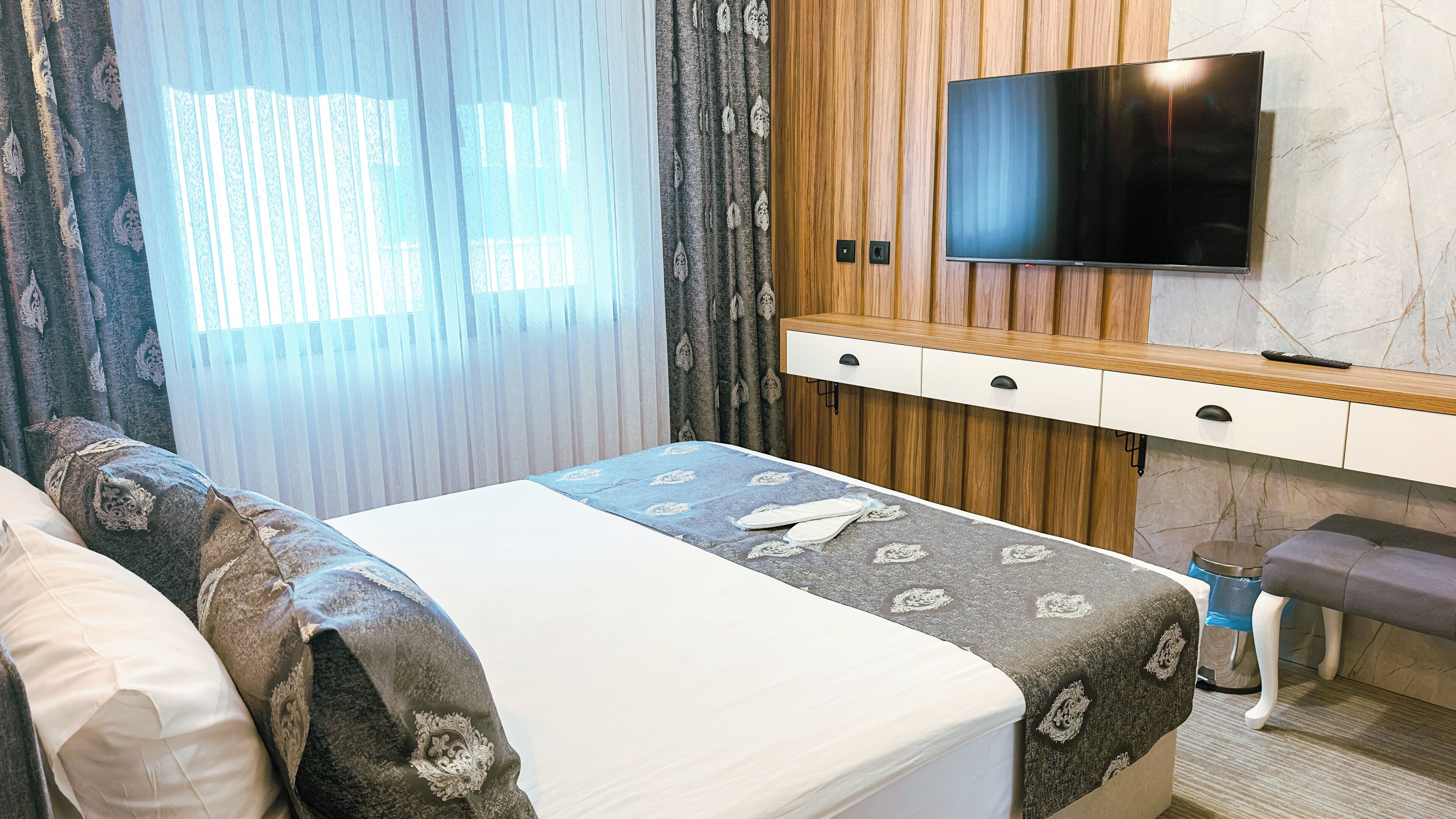 Una camera d'albergo con un letto, una televisione, un armadio in legno e un bagno.