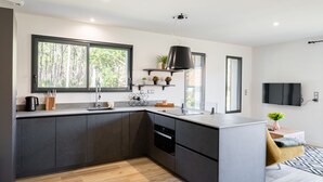 Eine moderne Küche mit dunklen Schränken, einem großen Fenster und einem eingebauten Backofen.