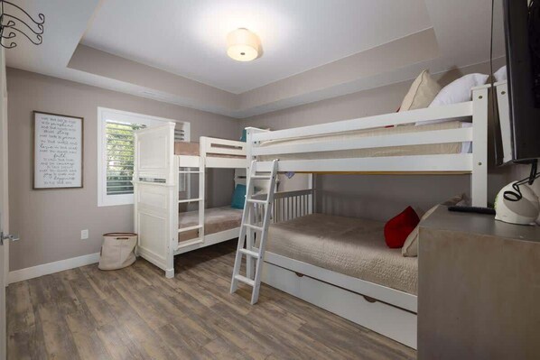 A bunk bed room with a ladder, a desk, and a window. - Estancia Pool Resort #W101 | Poolside View (Saint George)