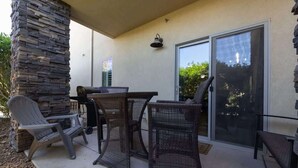 An outdoor patio with wicker furniture, a stone pillar, and a sliding glass door.