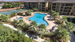 A hotel with a swimming pool surrounded by palm trees and a mountain view.