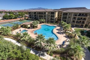 Ein Hotel mit Swimmingpool, umgeben von Palmen und Blick auf eine Berglandschaft.