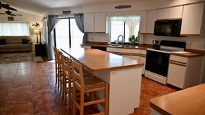 A compact kitchen with a central island, wooden chairs, a built-in oven, and a microwave. - Spacious Waterfront Home 3BR 2BA  Heated Pool  Boat Dock & Fishing (Port Charlotte)