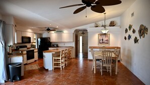 A spacious kitchen with a central island, a dining area with a wooden table and chairs, and a ceiling fan. - Spacious Waterfront Home 3BR 2BA  Heated Pool  Boat Dock & Fishing (Port Charlotte)
