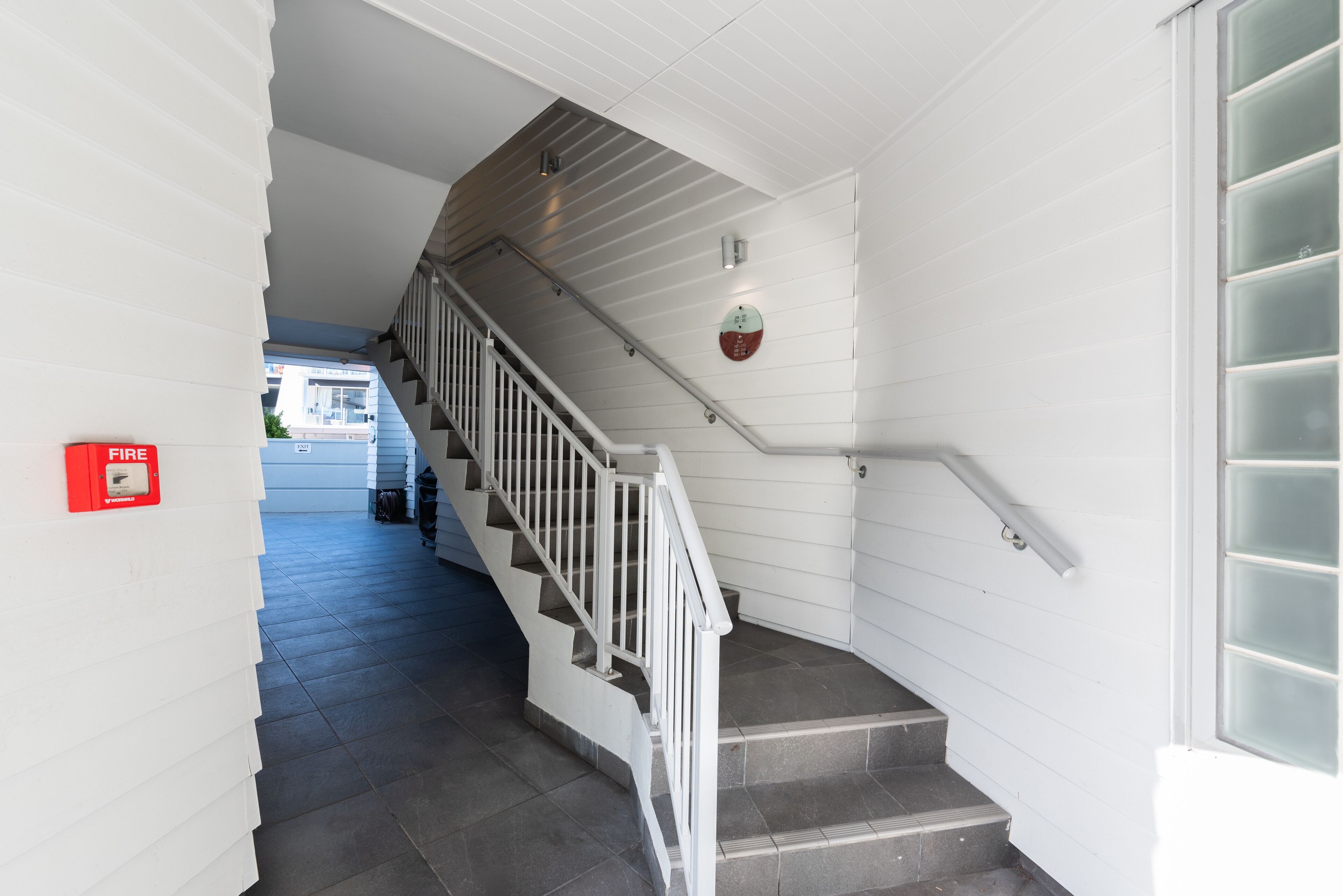 A staircase with white railings and a fire alarm on the wall.