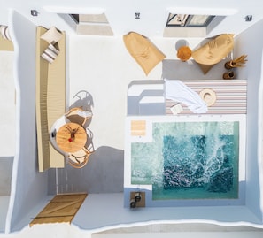 A modern, minimalist room with a large window, a wooden table with chairs, and a view of the ocean. - Electra Suites & Spa (Santorini)
