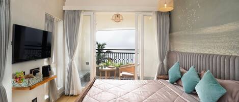 Un dormitorio con una cama grande, televisión, balcón con vistas y techo con vigas a la vista.