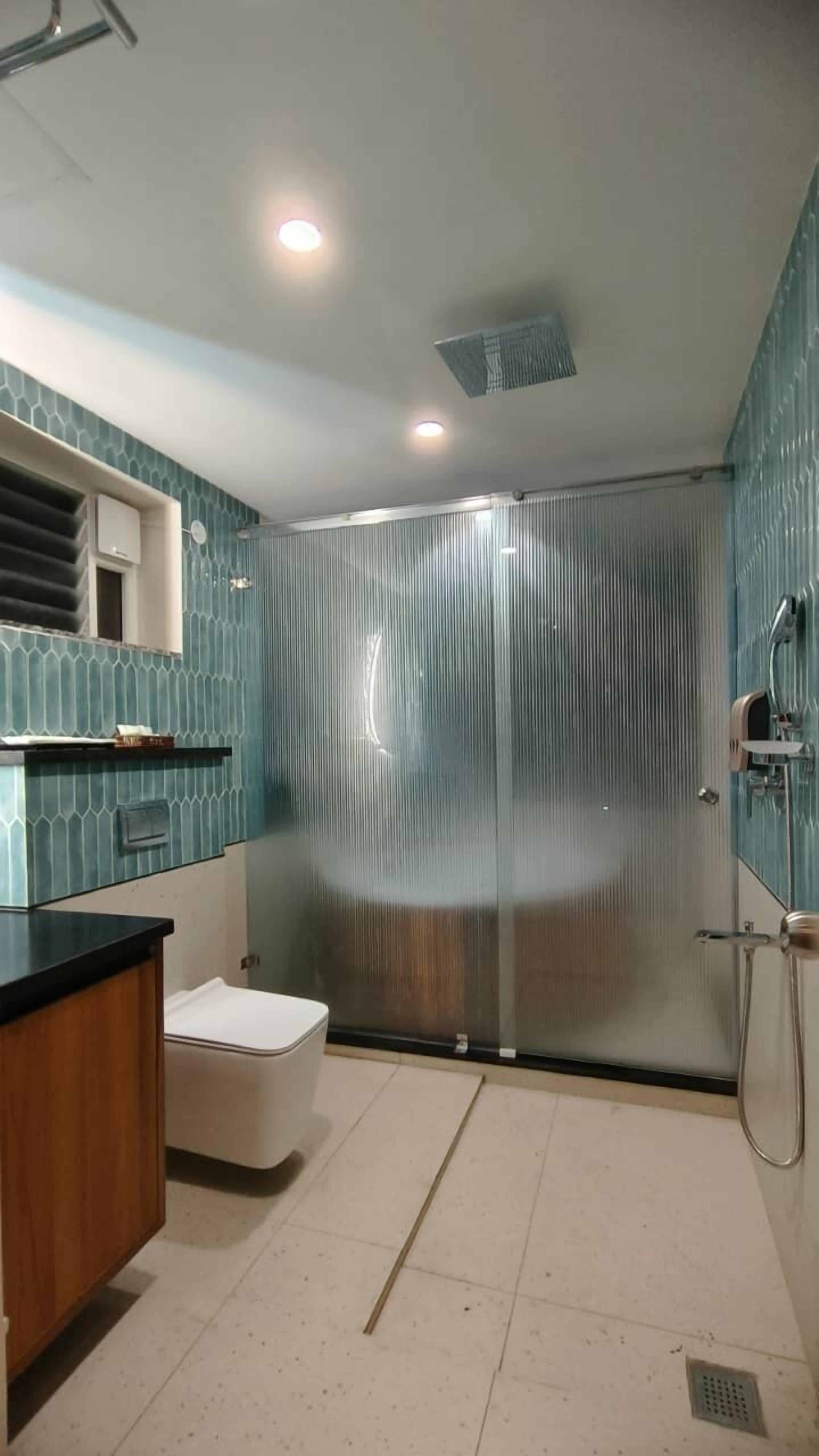 A modern bathroom with a glass shower enclosure, a white toilet, and a wooden vanity with a sink.