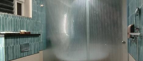 A modern bathroom with a glass shower enclosure, a white toilet, and a wooden vanity with a sink.