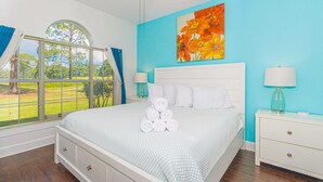 A bedroom with a bed, a nightstand, a window with blinds, and a painting on the wall. - MP101-Building 22 Magnolia (Myrtle Beach)