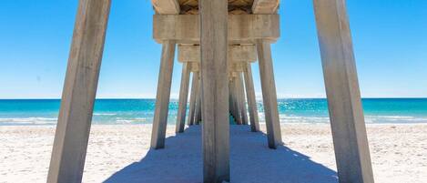 A concrete pier structure with multiple pillars leading to a beach.