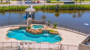 A swimming pool with a gazebo, surrounded by a fence and a landscaped area.