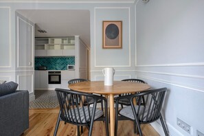 Cozy living space with a round table and four chairs, kitchen area, and artwork on the wall.
