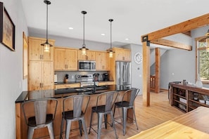 A modern kitchen with wooden cabinets, stainless steel appliances, and a central island with bar stools.
