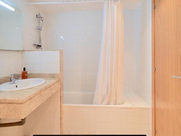 Un baño con lavamanos, espejo, ducha y puerta de madera.