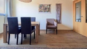 A dining area with a table and chairs, a hanging light fixture, a framed picture on the wall, and a patterned curtain. - Holidays2Malaga Heroe de Sostoa with pool view (Málaga)