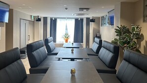 Una sala de conferencias moderna con una mesa larga y asientos de cuero negro.