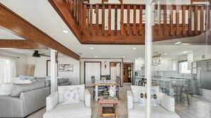 A spacious living area with a high ceiling, wooden beams, and a glass partition. - Family Reunions, Corporate/Church Retreats, Large Gatherings-Steps to the beach! (Freeport)