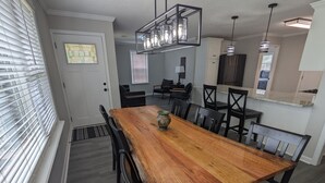 A dining area with a wooden table, black chairs, a vase, and a kitchen in the background. - Remodeled Bungalow walking distance to Augusta National (Augusta)