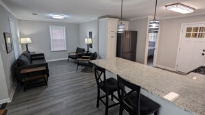 A modern kitchen with a granite countertop, black chairs, and a refrigerator. - Remodeled Bungalow walking distance to Augusta National (Augusta)
