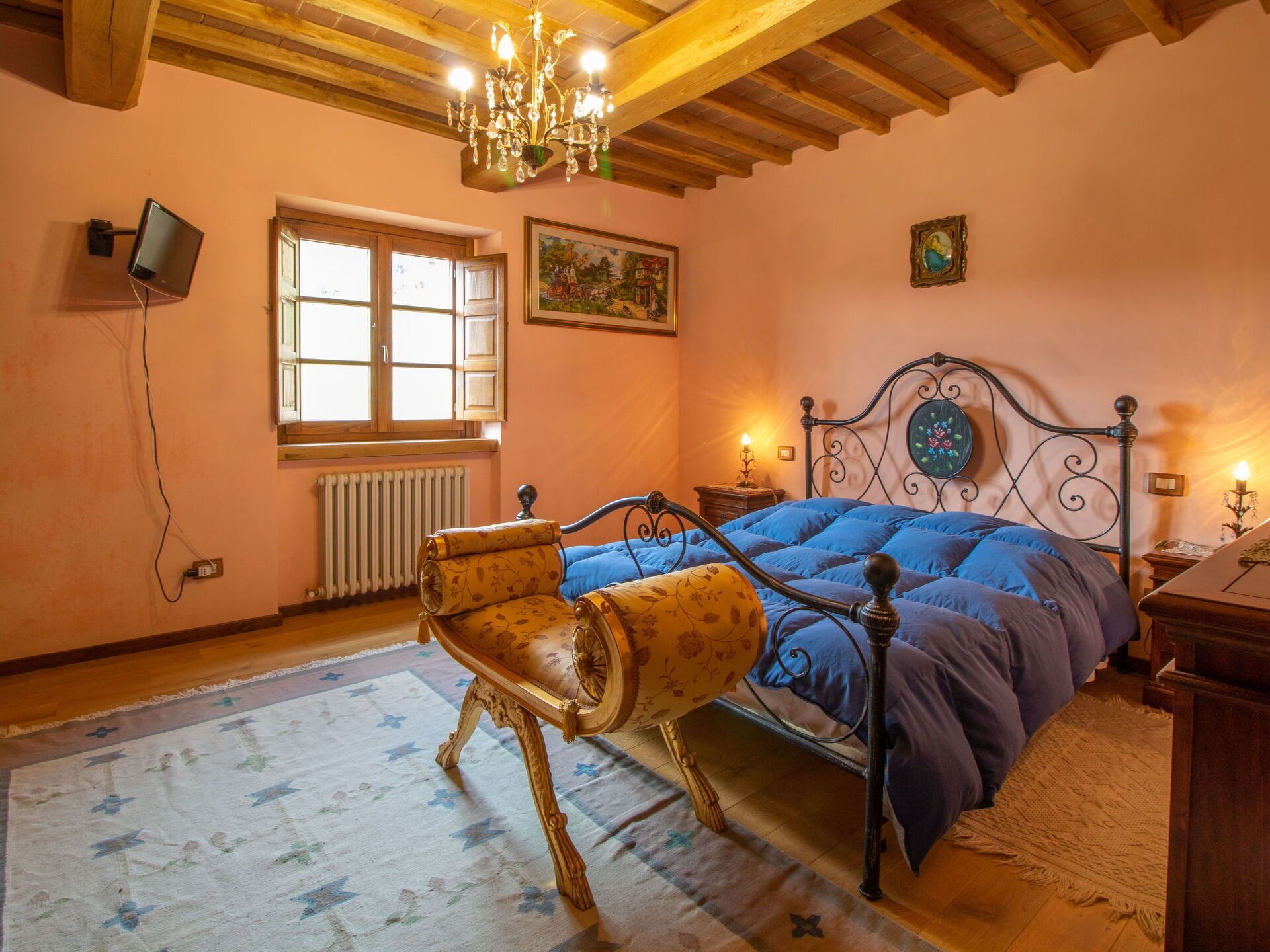 Ein Schlafzimmer mit Bett, Stuhl, einer Kandelaber, einem Fenster und einem Gemälde.
