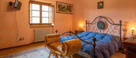 Ein Schlafzimmer mit Bett, Stuhl, einer Kandelaber, einem Fenster und einem Gemälde.