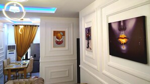 A modern interior with a dining area, a sofa, and artwork on the walls. - Kings' Place Lekki - 2Bedrooms (Lekki)