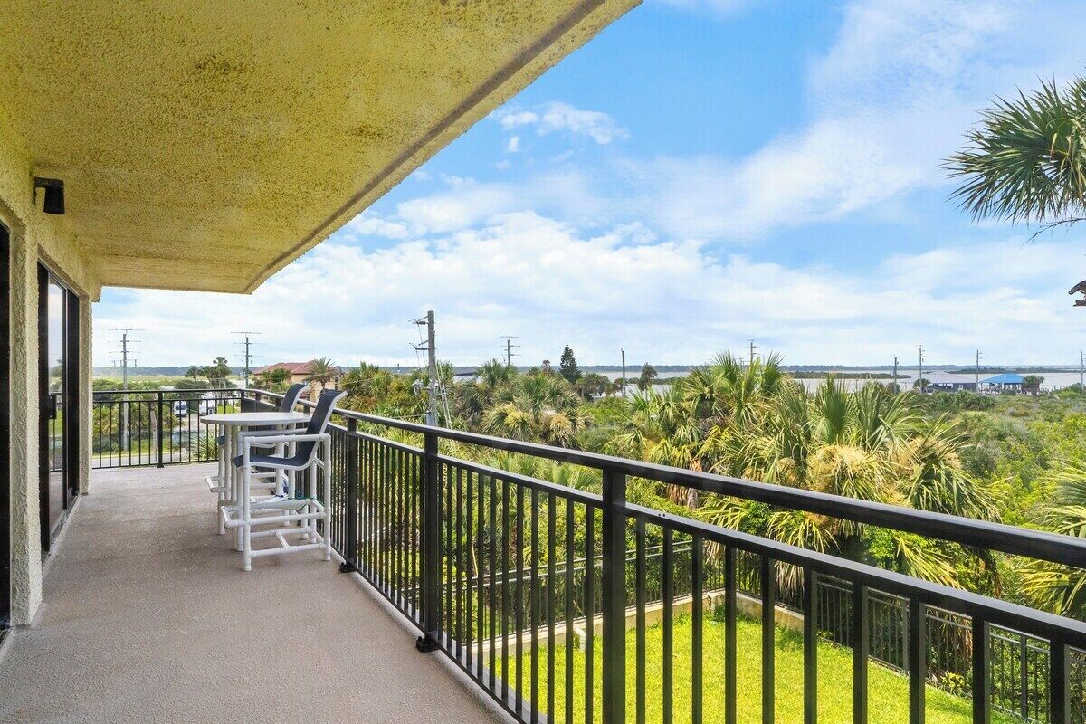 A balcony with a view of a green landscape and a body of water.